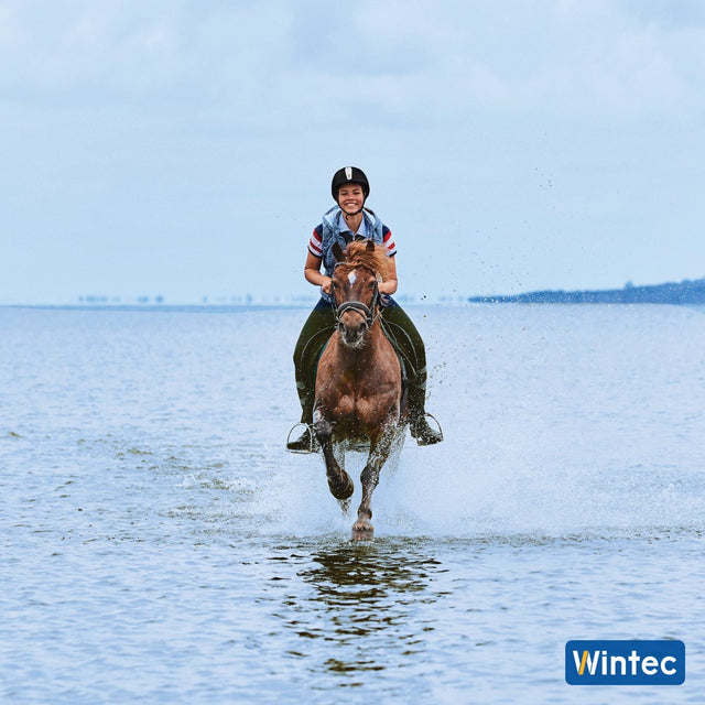 Rider cantering through the shallows in a Wintec saddle