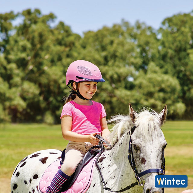 Young girl smiling on a spotted pony with the Wintec Kids Saddle Pack