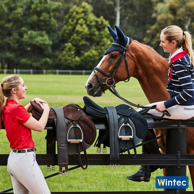 Riders with Wintec jump saddles on the fence beside a horse